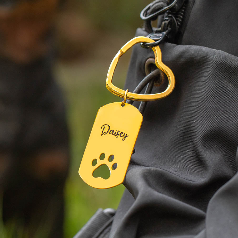 Custom gold dog tag keyring with text engraving hanging on backpack